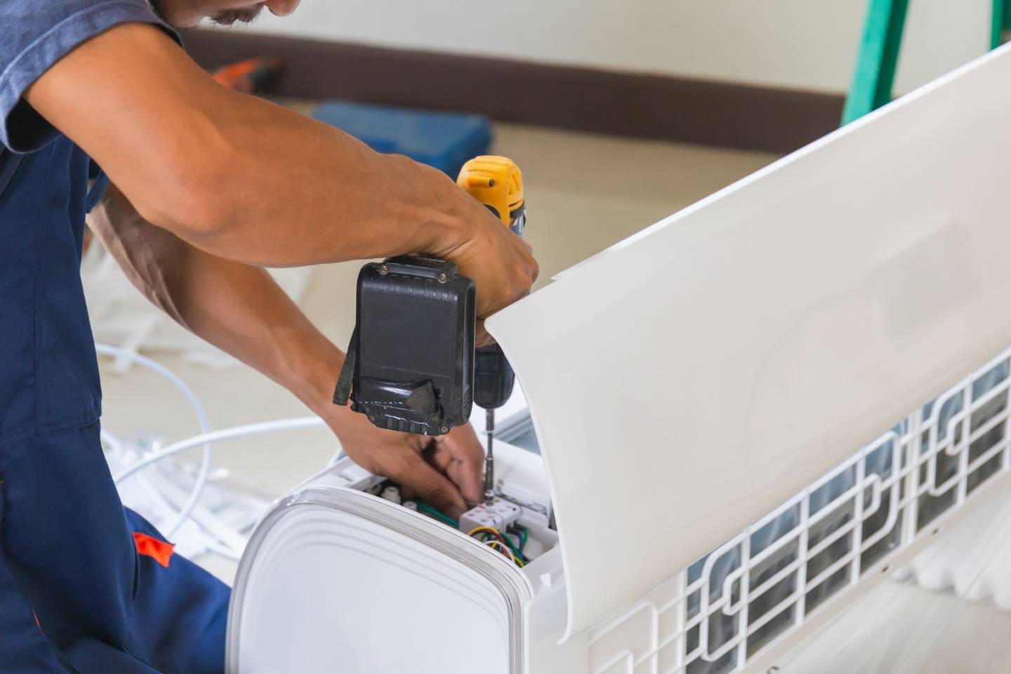 Atlanta Air Quality Services 1 A person expertly repairing an indoor air conditioning unit with a screwdriver, ensuring optimal performance and efficiency. Their attention to detail highlights the importance of regular maintenance and air duct cleaning for a healthy home environment.