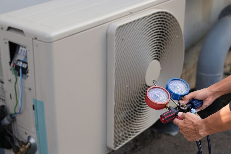 A technician expertly uses a manifold gauge set to check the pressure on an outdoor air conditioning unit, ensuring optimal performance in a commercial HVAC installation.
