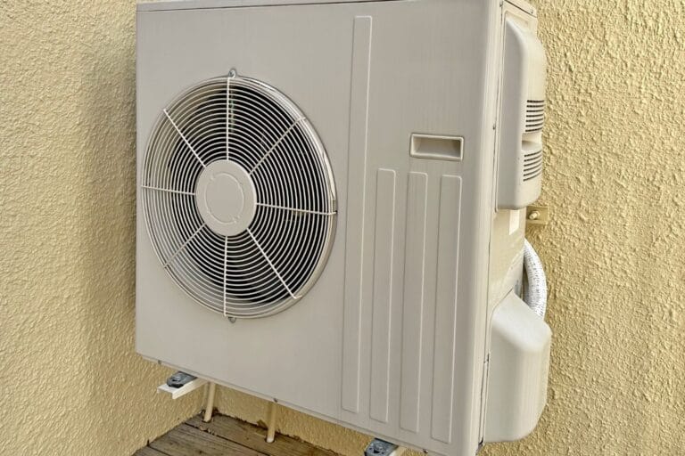 A Mini-Split system is mounted on a beige wall, featuring a large fan and several vents.