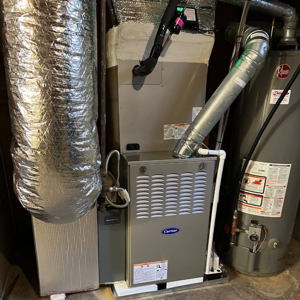A home HVAC system with a Carrier furnace, insulated ductwork, and a water heater in a utility room expertly installed by HVAC contractors in Georgia.