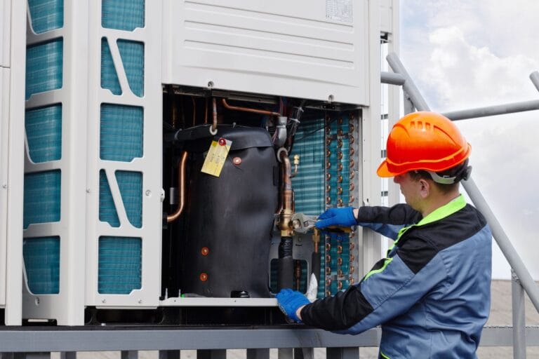 On a clear day, a technician in safety gear adjusts HVAC unit components on a rooftop, ensuring seamless residential maintenance.