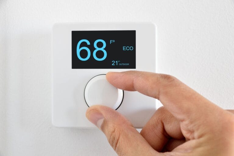 A hand adjusts a white thermostat, deftly set to 68 degrees Fahrenheit in eco mode, highlighting the widget's user-friendly interface.