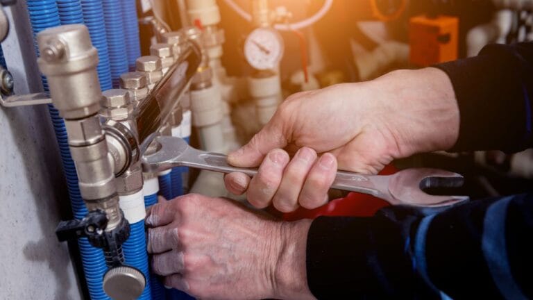 Air Conditioning Services in Sandy Springs 5 A person diligently works with a wrench, adjusting pipes and valves in a mechanical system, ensuring everything is perfectly set for emergency heating repair in Georgia.