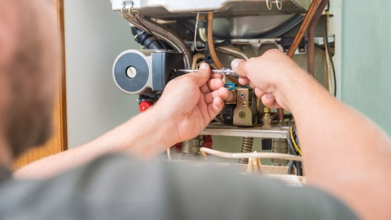 A skilled technician is using a wrench to repair a boiler, meticulously focusing on the pipes and components inside the unit. This precision is akin to the detailed approach required for furnace repair in Georgia, ensuring everything runs smoothly and safely.