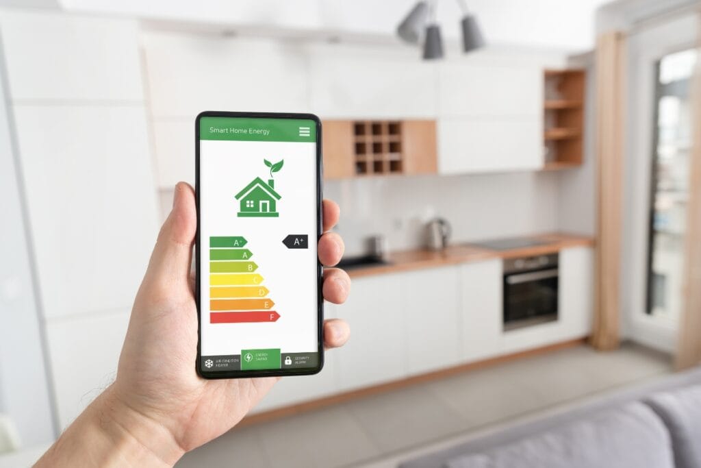 The Ultimate SEER Rating HVAC Guide: Why It’s Crucial for Efficiency 3 A hand holds a smartphone displaying a smart home energy efficiency app with SEER rating HVAC details in a modern kitchen.