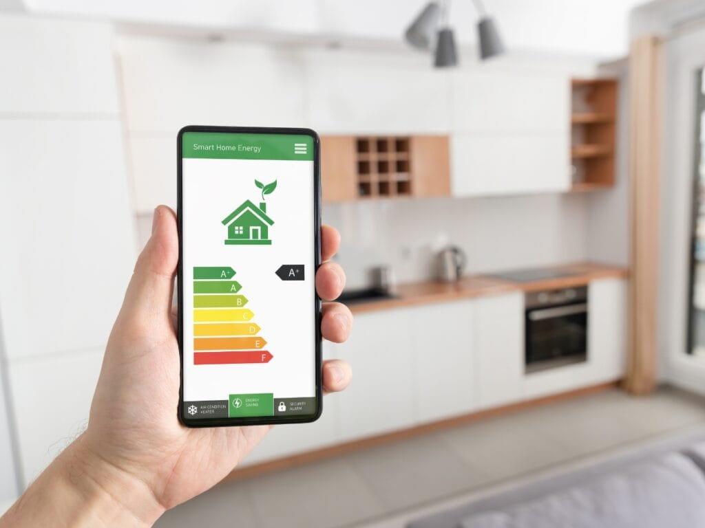 A person holds a smartphone displaying a smart home energy efficiency rating app with an integrated HVAC Checklist in a modern kitchen.