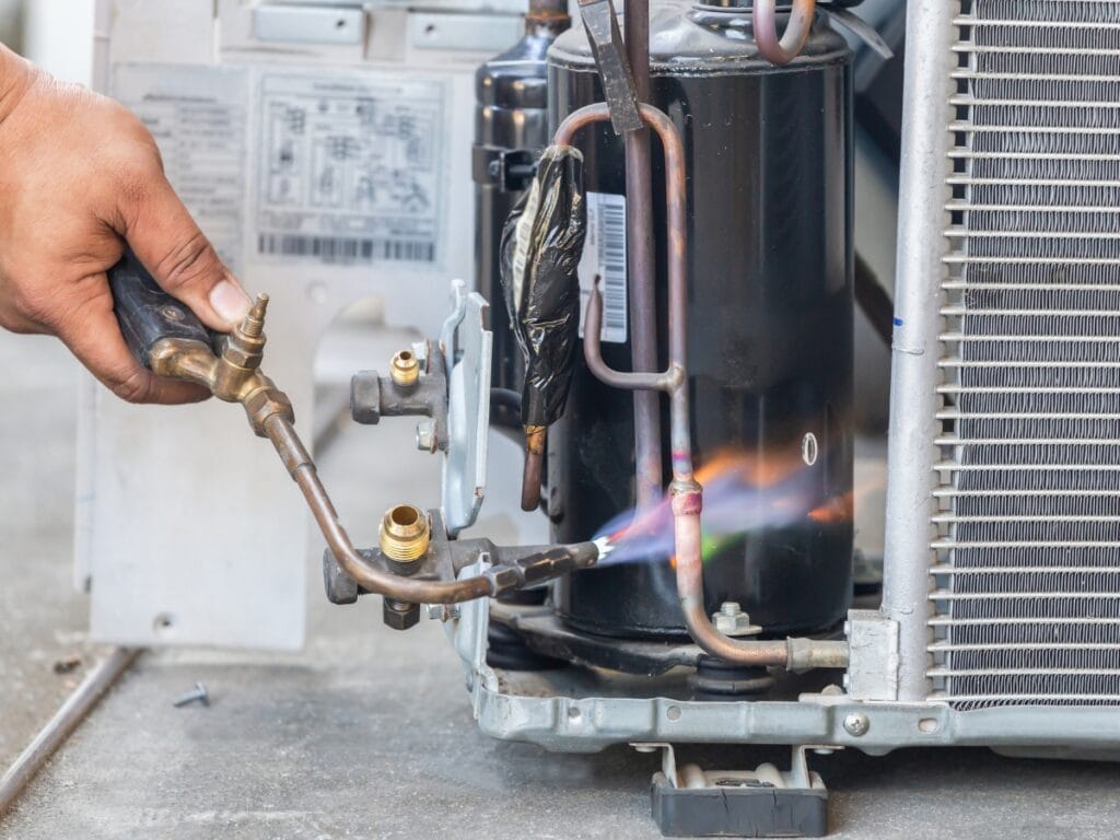 A person holding a gas burner, preparing for annual HVAC maintenance.
