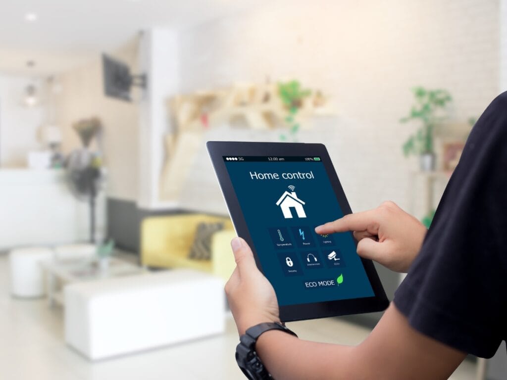 Smart Home HVAC Accessories: Best Gifts for Homeowners 3 Person using a tablet to control smart home automation features in a modern living room, with options for lighting, security, appliances, and smart home HVAC accessories displayed on the screen.